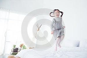 Little girl jumping on bed at home