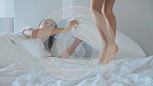 Little girl jumping on bed and wakes up her young mother in the early morning