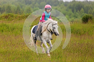 Little girl jumping on the field at a gallop