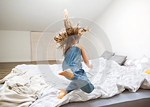 Little girl jumping at home on bed