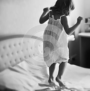 A little girl jumping on a king size bed