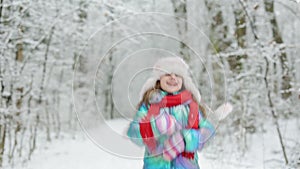Little girl jumping on the snow wearing snow clothes. Funny little girl in a colorful knitted hat and warm coat playing