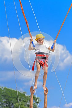 A little girl jumps high on a trampoline with rubber ropes again