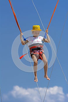 A little girl jumps high on a trampoline with rubber ropes again