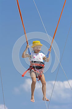 A little girl jumps high on a trampoline with rubber ropes again