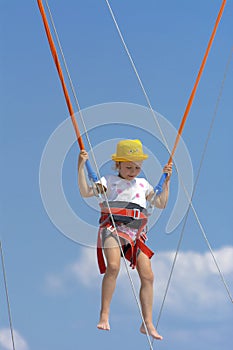 A little girl jumps high on a trampoline with rubber ropes again