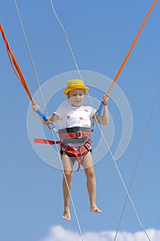 A little girl jumps high on a trampoline with rubber ropes again