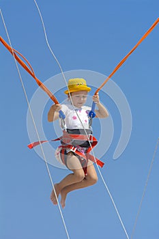 A little girl jumps high on a trampoline with rubber ropes again