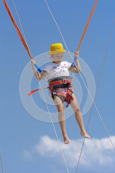 A little girl jumps high on a trampoline with rubber ropes again