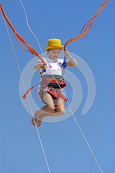 A little girl jumps high on a trampoline with rubber ropes again