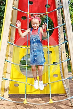 A little girl jumps high up on a children`s playground. happy child walks in summer