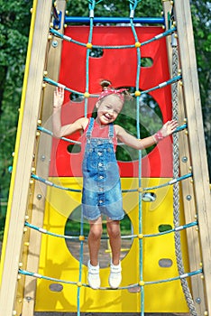 A little girl jumps high up on a children`s playground. happy child walks in summer