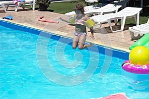 Little girl jumps in the pool; summertime background