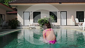 Little girl jumps in a swimming pool. funy time in summer holiday
