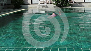 Little girl jumps in a swimming pool. funy time in summer holiday