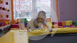 A little girl jumps on a trampoline in a play entertainment center for children.