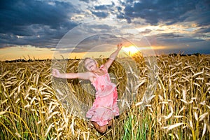 Little girl jumps in a wheat field.