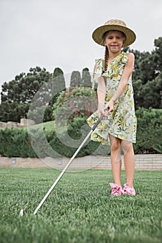 Little girl just swing golf ball on golf course fairway photo