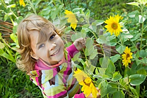 Little Girl keeps in hand sunflower in garden