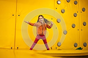 Little girl kid jumping on trampoline at yellow playground park. Child in motion during active entertaiments