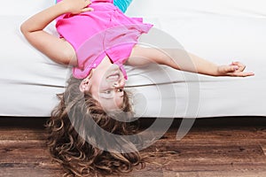 Little girl kid with long hair upside down on sofa