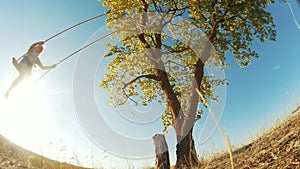 Little girl kid swinging on a wooden swing on a tree in the park. happy family kid dream concept fun. little kid girl