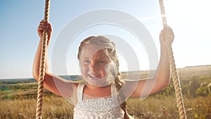 Little girl kid swinging on a wooden swing on a tree in the park. Happy family kid dream concept. Little kid girl