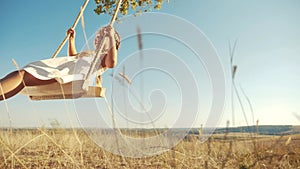 Little girl kid swinging on wooden swing a tree in the park. happy family kid dream concept. little kid girl playing on