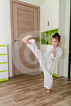 A little girl in a kimono goes in for sports - karate in her room.