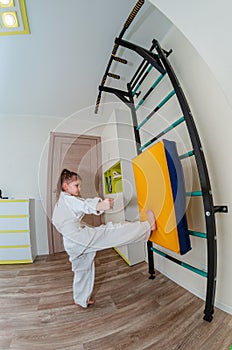 A little girl in a kimono goes in for sports - karate in her room.