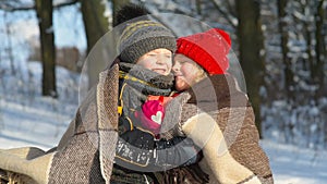 Little girl kissing boy with gift outdoors.