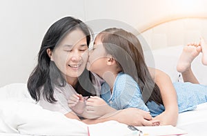 Little girl is kissing her beautiful young mom in cheek