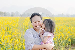 Little girl kissing her mom in flower field