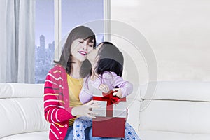 Little girl kissing her mother with gift