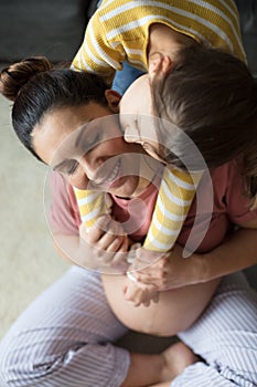 Little girl kissing and hugging pregnant her mom