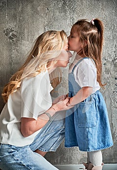 Little girl kissing mother forehead at home.