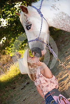 Little girl kissing pony.