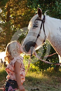 Little girl kissing pony.