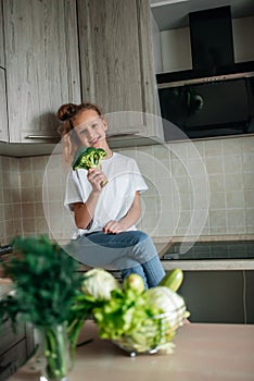Little girl the kitchen. Green fresh vegetables and salad, healthy food