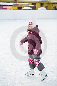 Little girl in knee pads skating at the rink