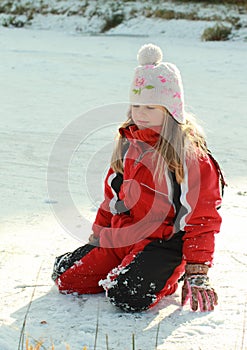 Little girl kneeing on iced pond photo