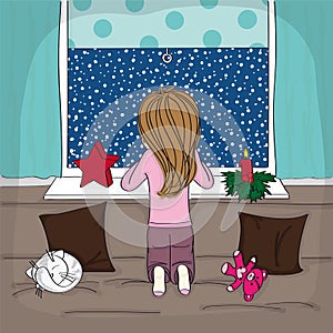 Little girl kneeling on the sofa looking out of the window to the night winter scenery