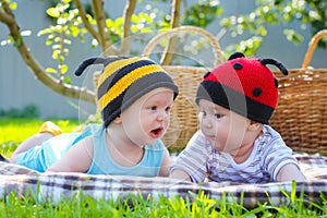 Little girl in knitted ladybird hat and boy playing outdoors, best friends, happy family, love and happiness concept