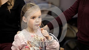 Little girl-lady paints lips with lipstick