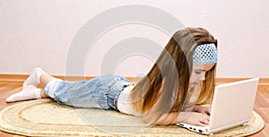 Little girl with a laptop at home on the floor