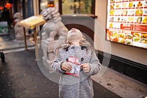 Little girl laughing hysterically with the statue of a Chinese dragon behind her