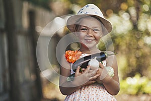 Little girl laughs with an armful of homemade vegetables, autumn harvest