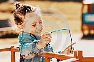 little girl laughs on a park bench. Fashionable baby