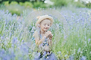 Little girl in lavender field. kids fantasy. Smiling girl sniffing flowers in summer purple lavender field