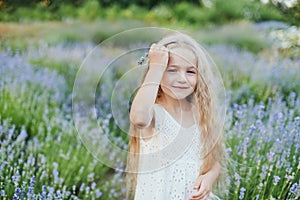 Little girl in lavender field. kids fantasy. Smiling girl sniffing flowers in summer purple lavender field